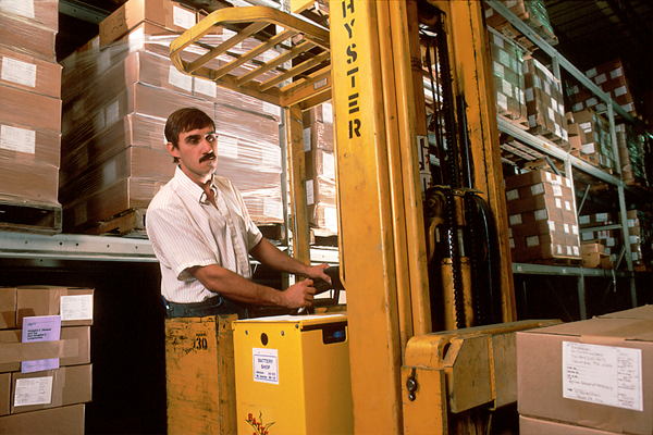 Photo of a warehouse distribution center employee driving a forklift